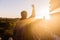 Young man raising hands up against sunlight - indicated success, achievement and victory.