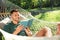Young man reading book in comfortable hammock at garden