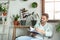 Young man reading book in room with home plants