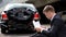 Young man reading insurance document sitting road on broken car background