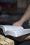 A young man reads the Bible, laying it on a wooden plank of boards.