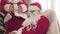 Young man in red costume sleeping in rocking chair as unrecognizable Santa Clause laughing at the background holding