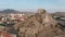 Young man with remote control flies contemporary drone standing on hill slope in ancient Sudak city on sunny day aerial