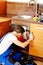 Young man repair something inside kitchen cabinet under the sink