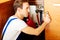 Young man repair something inside kitchen cabinet under the sink