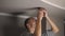 young man repairing cable wiring and installs or replaces the halogen lamp on the ceiling