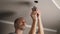 A young man is repairing a ceiling soffit. Replacing the LED lamp at the downlight