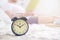 Young man resting on a beed reading a book. Alarm clock