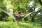 Young man resting in comfortable hammock at garden