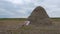 Young Man Resting Near Huge Haystack In The Field. A Man Sits Leaning On A Haystack And Looks Around Enjoying Life