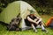 Young man resting in tent while hiking in green forest