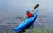 Young man riding around lake on kayak