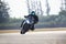 Young man riding big bike motorcycle against sharp curve of asphalt high ways road with rural lake scene use for male adventure ac