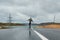 Young man riding a longboard on empty winding mountain road in summer, rear view.