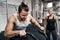 Young man riding a stationary bike with his gym partner