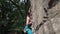 Young man rock climber with naked torso climbs on a granite cliff, gripping hold but falling