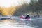 young man rowing canoe in early spring morning. lifestyle. Morning landscape, fog by the morning river and people on the