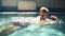 Young man rowing under the water with his blonde son on the back. Little boy is above the water. Indoors swimming pool