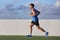 Young man runner running in city park on summer grass outdoors at sunset at outdoor stadium fitness centre. Healthy lifestyle