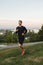 Young man running outdoors, at sunset, staying active