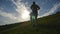 Young man running over green hill over blue sky background. Male athlete is jogging in nature at sunset. Sports runner