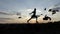 Young man runs and drives away doves at a lawn at sunset in slo-mo