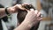 Young man`s haircut in Barbershop. Close-up of master clipping hair with scissors and comb