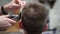 Young man`s haircut in Barbershop. Close-up of master clipping a man with blond hair with clipper