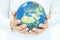 Young man\'s hand holding a globe, showing the world\'s healing, protecting the planet from global warming
