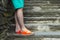 Young man& x27;s legs with neon orange slippers standing on stone stairs