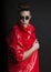 Young man`s portrait. Stylish handsome Guy in fashionable red lacquer raincoat and round sunglasses