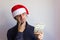 Young man with Santa hat holding one dollar bills with displeasure look