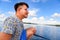 Young man seating on a main deck of a sailboat, sailing on a lake. Summer vacations, cruise