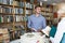 Young man seller helping customer in book store