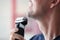 Young man shaves with electric razor closeup
