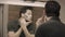 Young man shaving face in front of mirror at bathroom. Portrait of handsome guy