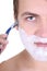 Young man shaving with razor close up