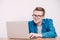 Young man in shirt and glasses he looks at the laptop in amazement and with a funny face sitting at the table on a white