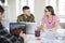 Young man in shirt and woman in striped t-shirt and eyeglasses happily discussing work moments together. Group of cool