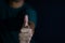 Young man showing gesture thumbs up or giving approval on dark black background. selective focus on finger