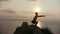 Young man silhouette doing squats on the cliff at sunrise
