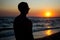 Young man silhouette facing a beautiful sunset at the beach