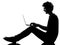 Young man silhouette sitting computing laptop