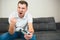 Young man sit in room during quarantine. Emotional guy playing computer games. Male person hold joystick in hand and