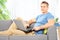 Young man siting at home on a sofa with laptop