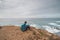 Young man sits above the famous Praia da Carreagem beach in southwest Portugal, near the town of Aljezur in the Odemira region.