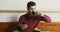 A young man sits in a cafe and uses phone, from time to time looking around