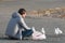 Young man sits on the ground and feeds seagulls