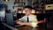 A young man sits in the kitchen at the bar counter and works in a laptop