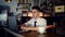 A young man sits in the kitchen at the bar counter and works in a laptop